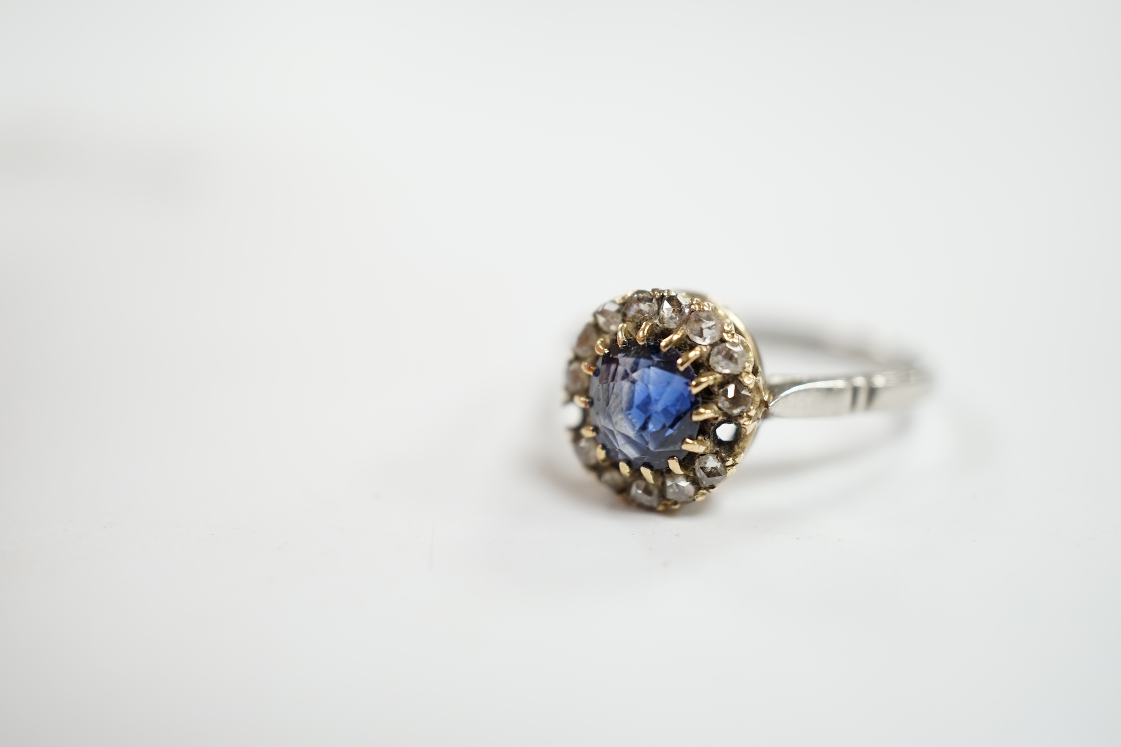 An early 20th century white metal (stamped plat), sapphire and diamond set cluster ring, size O, gross weight 3.6 grams. Condition - poor (two stones missing)